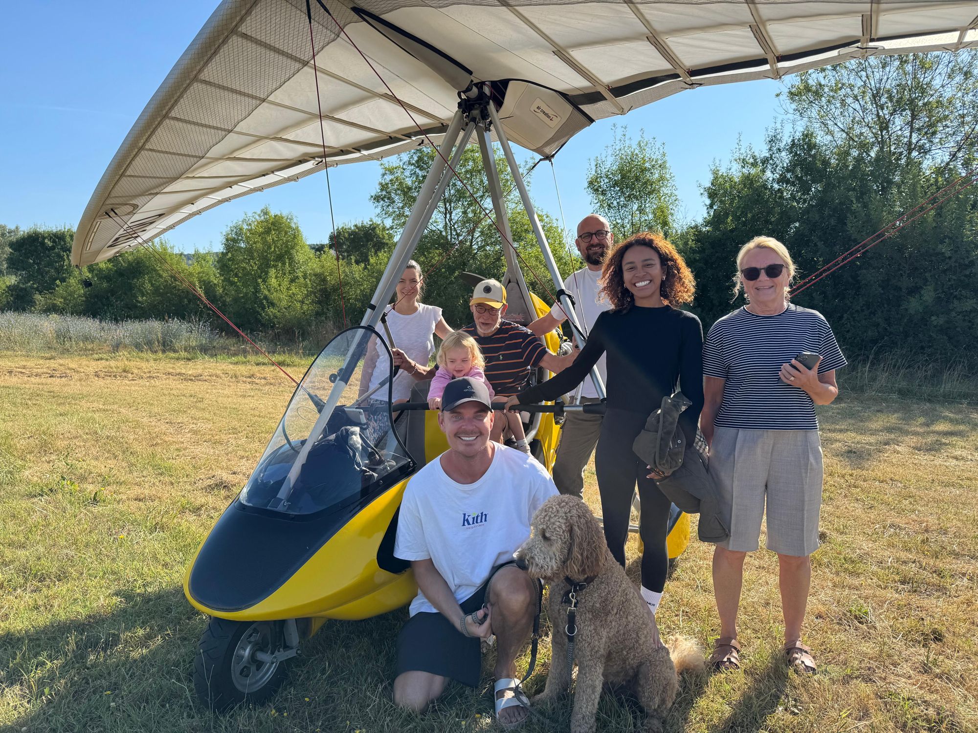 Une famille souriante posant devant un ULM pendulaire jaune